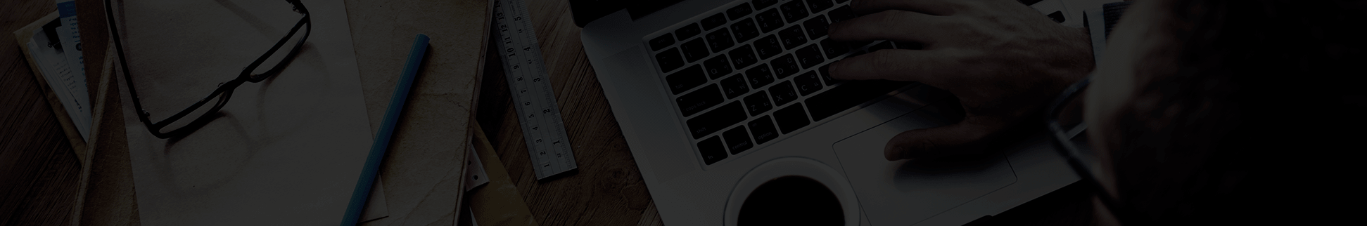 Una persona usa una computadora portátil con papeles, anteojos, una regla y un lápiz sobre una mesa cercana, trabajando diligentemente en estrategias de detección y respuesta administradas.