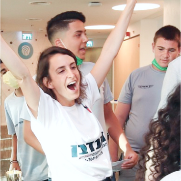  Un grupo de personas con camisas blancas y grises se encuentran en el interior de una casa. Una mujer con camisa blanca y los brazos en alto sonríe con energía, reflejando el dinamismo de Google Chronicle. Otras personas se encuentran de pie a su alrededor con naturalidad, como si se tratara de un equipo que trabaja en conjunto en soluciones de xDR gestionadas adaptativas.