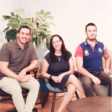  Three people are sitting in chairs in a bright room with a plant in the background. They are smiling and appear relaxed, discussing their latest success with adaptive managed xDR solutions.