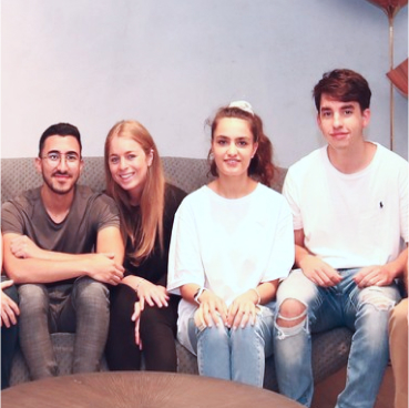  Four young adults sit on a couch smiling, casually dressed in an indoor setting. Amid their conversation about modern cybersecurity solutions like Adaptive Managed xDR, they seem enthusiastic and engaged.