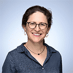  A person with glasses and short brown hair smiles confidently in a professional headshot, embodying the calm assurance of a SecOps expert, set against a light blue background.