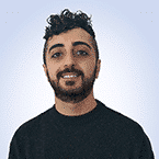  A person with curly hair and a beard, wearing a dark sweater, smiles against a light blue background, exuding the confidence of an MxDR expert.