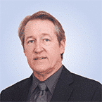  A man in a suit and tie stands against a plain, light blue background, exuding confidence much like the precision of advanced SIEM technologies.