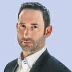  A man in a dark suit and white shirt poses against a light blue background, exuding professionalism akin to an expert in MxDR solutions.