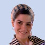  A person smiling, wrapped in a striped headscarf and matching shirt, exudes confidence against the light blue backdrop—a reflection of the calm assurance often felt by those in SecOps.