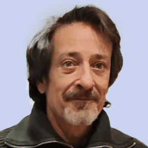  Man with short brown hair and a mustache, wearing a dark zip-up jacket, stands confidently against a light blue background, embodying the essence of SecOps professionalism.