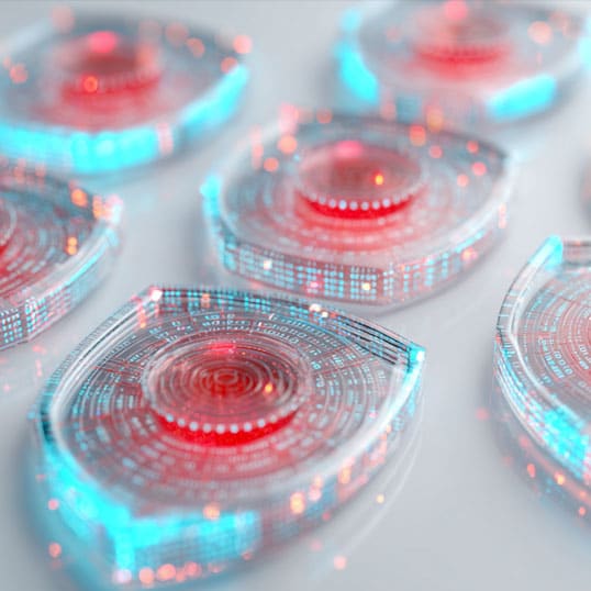  Close-up of several transparent shield-shaped objects with red and blue illuminated digital patterns, symbolizing advanced threat detection, arranged on a white surface.