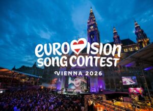 Large outdoor crowd and stage with “Eurovision Song Contest Vienna 2026” text overlay, set against illuminated historic buildings at dusk, capturing the excitement and anticipation for Eurovision 2026.